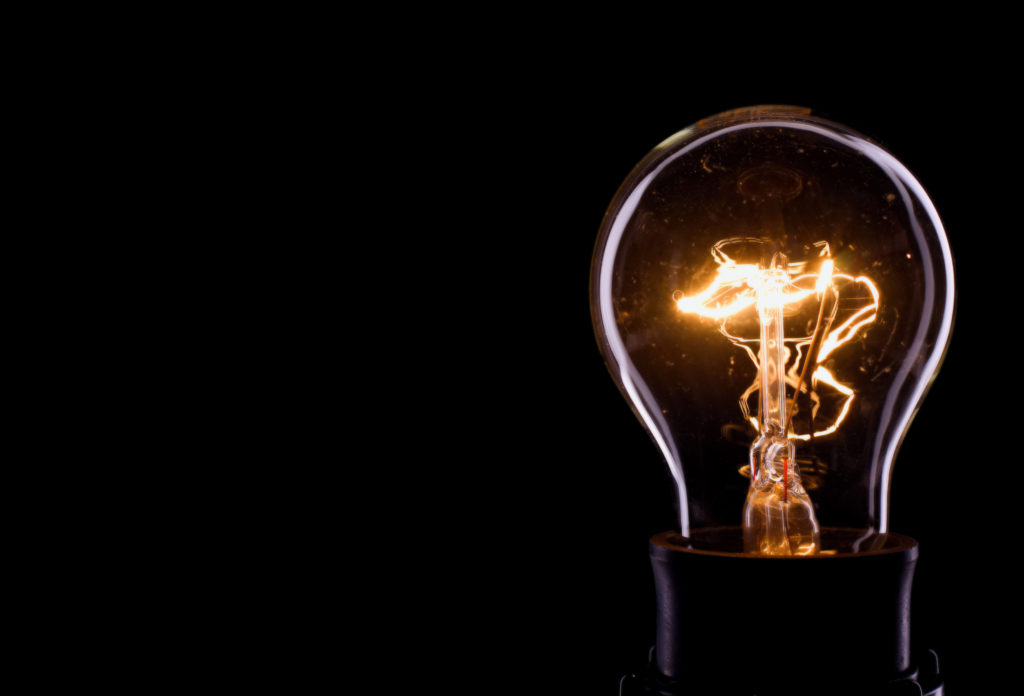 Lightning inside a glass bulb Horizontal photo of a bulb on black background. Only outline of a glass bulb is visible and inner part with lighted wire is there.